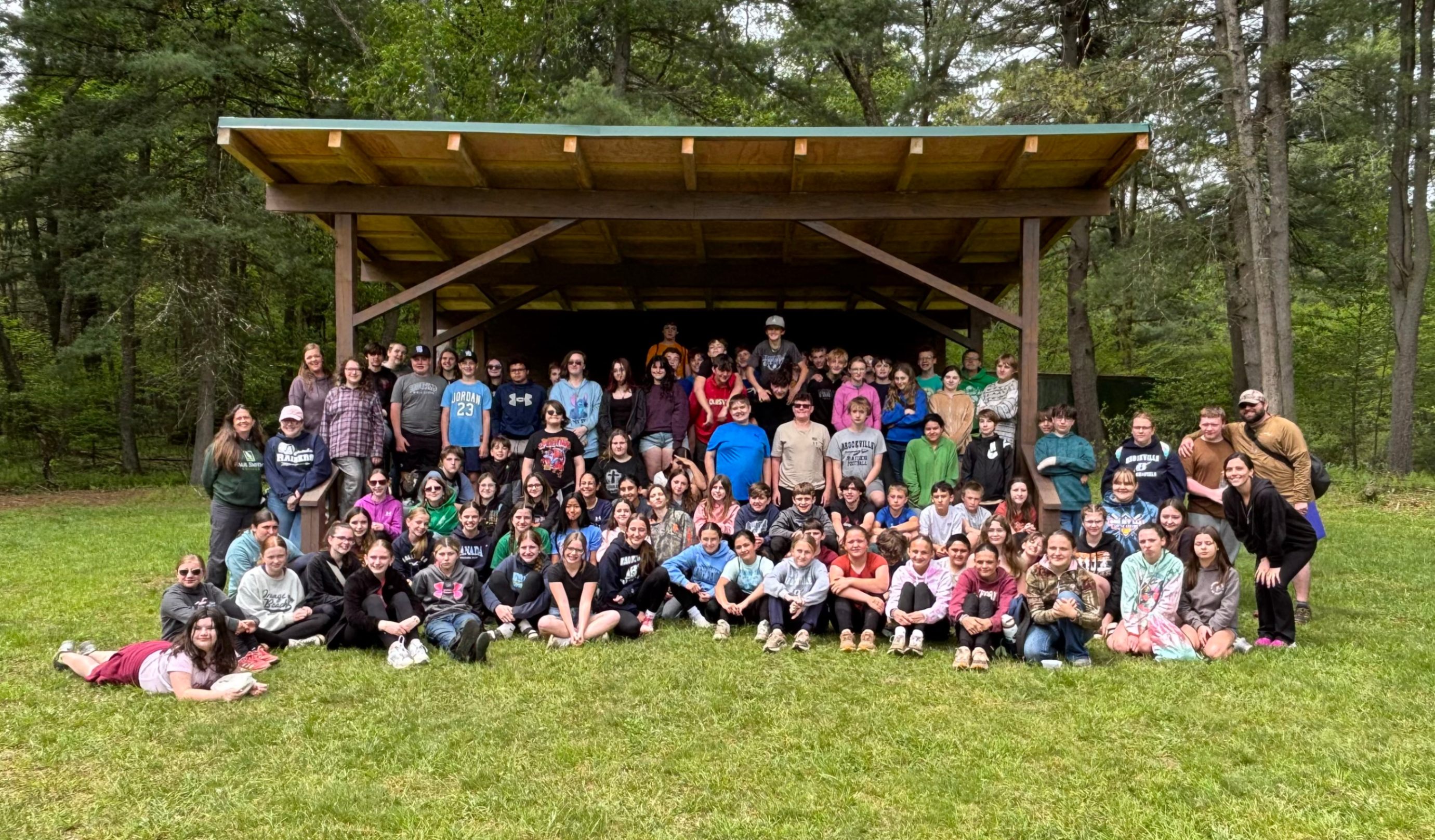 7th graders and chaperones pose for a group photo at YMCA Camp Coffman.
